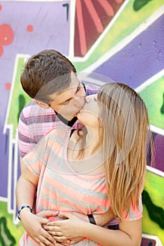 Young couple kissing near graffiti background.
