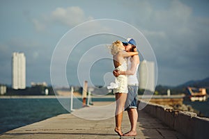 Young couple kissing on the pier against the sea. honeymoon lovers.