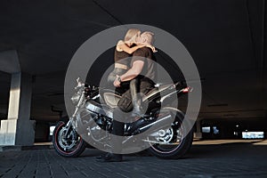 Young couple kissing sitting on a motorcycle in underground parking garage