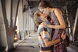 Young couple kissing in the summer daylight on a bridge construction in the city outdoors. copy space