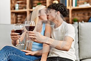 Young couple kissing and toasting with red wine glass at home
