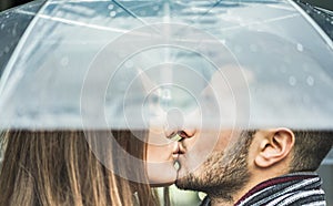 Young couple kissing under umbrella in a rainy winter day - Millennials lover having tender moments outdoor - Love, trends, fall,