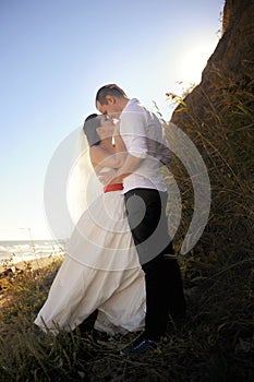 Young couple kissing in wedding gown, outdoor