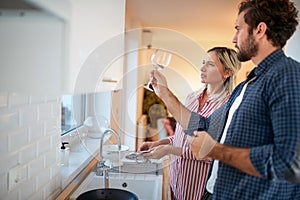 A young couple likes cleanliness of the dishes to the details. Kitchen, housework, home, relationship