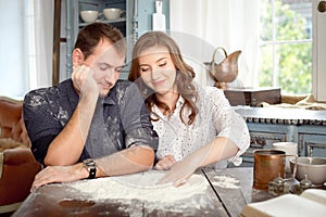 Young couple in the kitchen playing with flour. Funny moments, smiles, cooking, Happy together, memories.