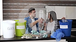 Young couple in kitchen during quarantine. Young man and woman sorting garbage with responsibility. Separating plastic