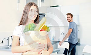Young couple in the kitchen , woman with a bag of groceries shopping.