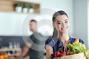 Young couple in the kitchen , woman with a bag of groceries shopping