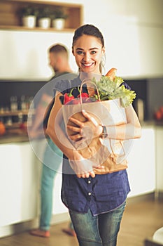 Young couple in the kitchen , woman with a bag of groceries shopping