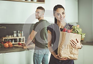 Young couple in the kitchen , woman with a bag of groceries shopping