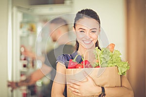 Young couple in the kitchen , woman with a bag of groceries shopping