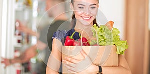 Young couple in the kitchen , woman with a bag of groceries shopping