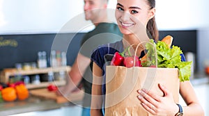 Young couple in the kitchen , woman with a bag of groceries shopping