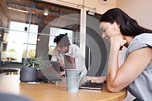 Young couple with laptops at desks preparing for online meeting in rented open plan office space