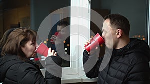 Young couple in the late afternoon drinking red plastic glasses on the balcony