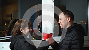Young couple in the late evening drinking a drink on the balcony of plastic glasses