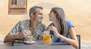 Young couple laugh while drink a smoothy and a coffee. Husband and Wife smiling, sitting in a bar. Lovers together, dating and