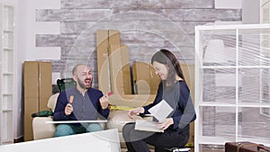 Young couple laughing while assembling furniture in their apartment