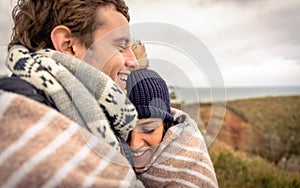 Young couple laughing outdoors under blanket in a