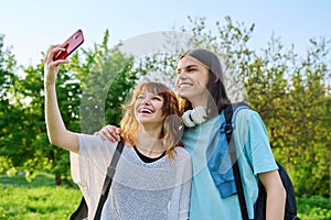 Young couple, laughing teenagers taking selfie photo on smartphone