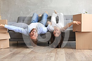 Young couple laying on the sofa with heads relaxing upside down smiling at the camera in the living room at moving day