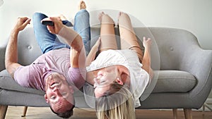Young couple laying on the sofa with heads upside down