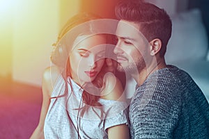 Young couple listening music by headphones together at home in s