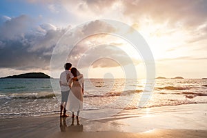 Young couple looking beautiful sunset on the tranquil beach, Summer vacation concept