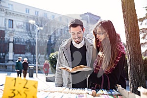 Young couple looking at book in the street
