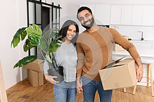 Young couple looking at the camera while moving to a new apartment together. Sweet home, moving to new apartment