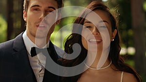 Young couple looking at camera in park. Bride and groom standing in garden.