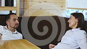 Young couple looking at each other and smiling while sitting in a cafe