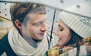 Young couple looking at each other under umbrella