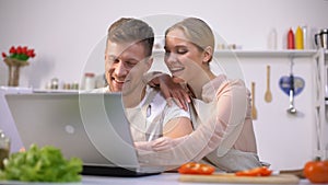 Young couple looking for food recipes on websites and laughing, kitchen novices