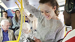 Young Couple Looking At Mobile Phone On Crowded Bus