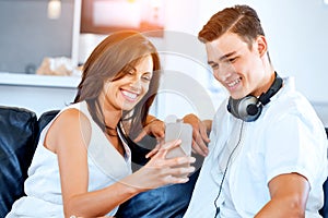 Young couple looking at mobile phone while sitting at home