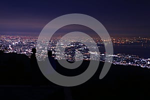 Young couple looking at the night city lights from the top of mountain