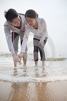 Young couple looking at seashells on the beach