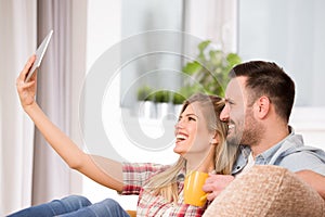 Young couple looking at tablet and laughing at home