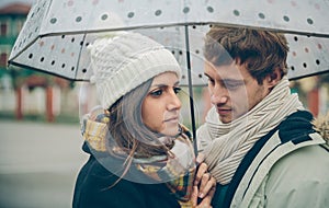 Young couple looking under umbrella in a rainy day