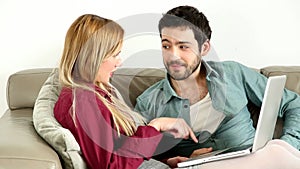 Young couple lounging on couch with laptop at home