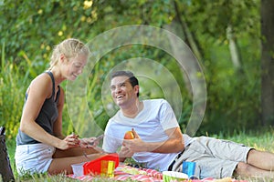 Young couple lounging in sunny spring day at picnic outdoors