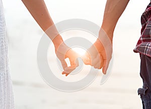 Young couple in love, Attractive man and woman enjoying romantic evening on the beach, Holding hands watching