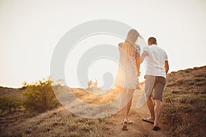 Mladý pár v láske, atraktívne mužov a žien sa teší romantický večer, držanie rúk, aby sa pozerať na západ slnka.