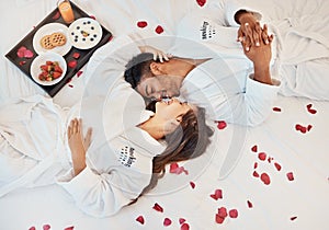 Young couple love on bed, with flowers and healthy snack on tray while on holiday. Man and woman, romance together in