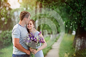 Young couple in love with a bouquet of flowers on a background of the path