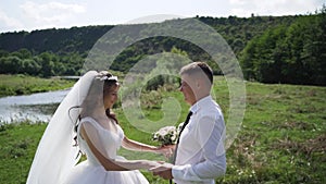 Young couple in love bride and groom, wedding day near a river. Steadycam shoot