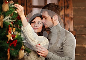 Young couple in love decorates Christmas tree at home