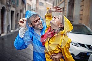 A young couple in love is enjoying the rain while walking the city during a rainy day. Walk, rain, city, relationship