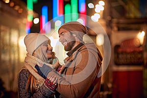A young couple in love is enjoying a time they are spending together while walking the city during christmas holidays. Christmas,